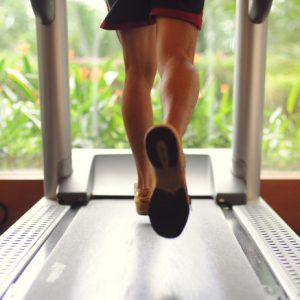 7 exercises: A person running on a treadmill in a gym to lose weight and feel great.