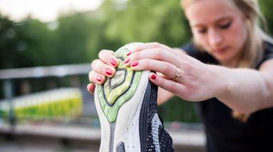 A woman is actively incorporating fitness into her healthy lifestyle by putting on her shoe.